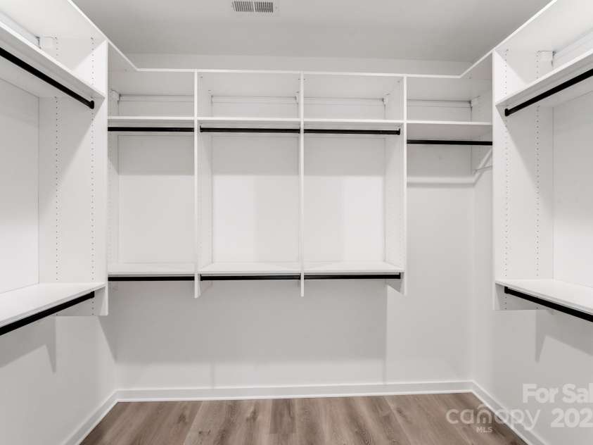 6907 Lancaster Highway, Waxhaw, NC 28173.  MLS# CAR4247480, YatesRealty ID 26742. A large walk-in closet features sleek black hanging rails and crisp white custom shelving, offering both modern style and functional organization.