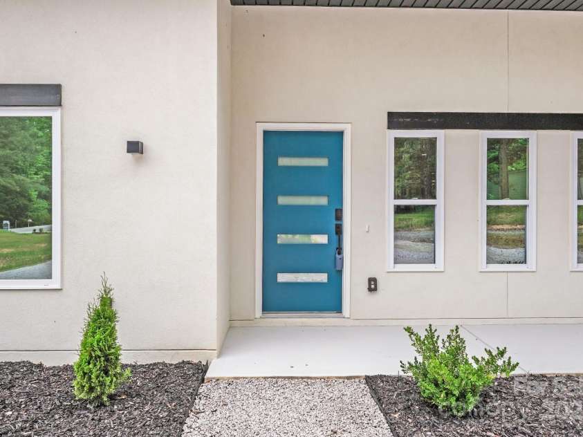 6907 Lancaster Highway, Waxhaw, NC 28173.  MLS# CAR4247480, YatesRealty ID 26742. A modern wall-mounted solar light, cheerful blue front door, and attractive windows create a charming and welcoming front exterior.