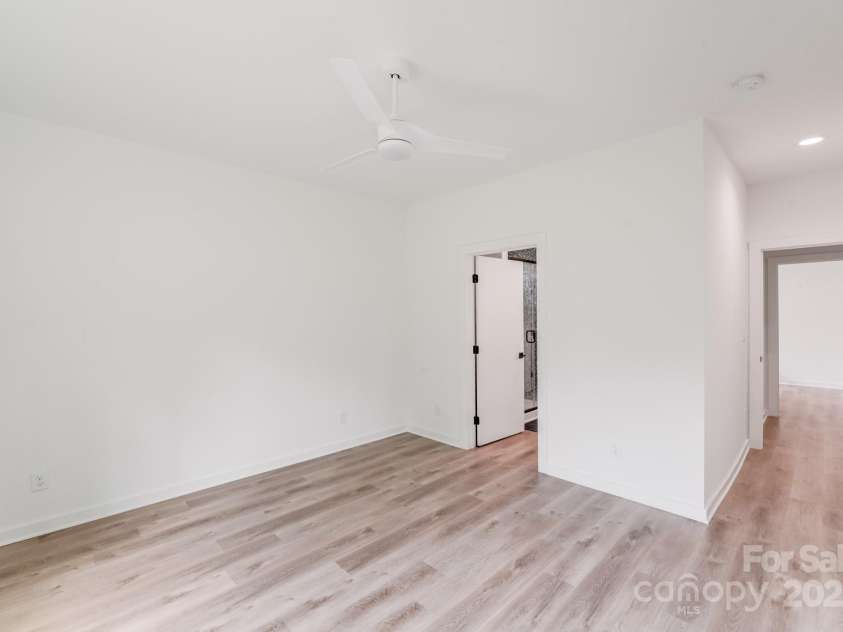 6907 Lancaster Highway, Waxhaw, NC 28173.  MLS# CAR4247480, YatesRealty ID 26742. Designed for privacy and comfort, the primary bedroom is tucked away with its own private entry hallway and en-suite bathroom. A sleek modern white ceiling fan adds a stylish touch to the serene, light-filled space.