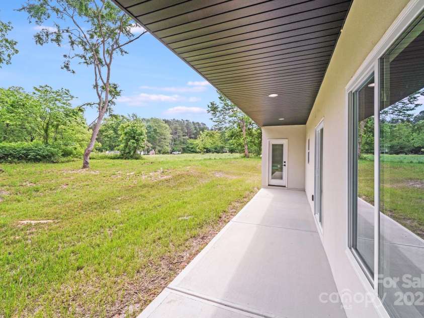 6907 Lancaster Highway, Waxhaw, NC 28173.  MLS# CAR4247480, YatesRealty ID 26742. From under the covered porch, enjoy a view of the large, level backyard framed by perimeter trees, offering a perfect blend of open space and natural privacy.