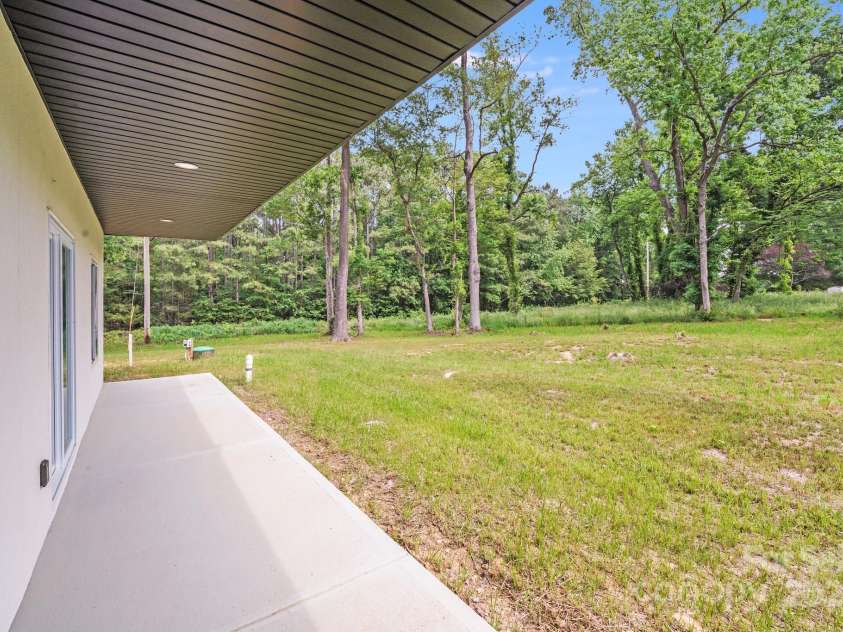6907 Lancaster Highway, Waxhaw, NC 28173.  MLS# CAR4247480, YatesRealty ID 26742. From under the covered porch, enjoy a view of the large, level backyard framed by perimeter trees, offering a perfect blend of open space and natural privacy.