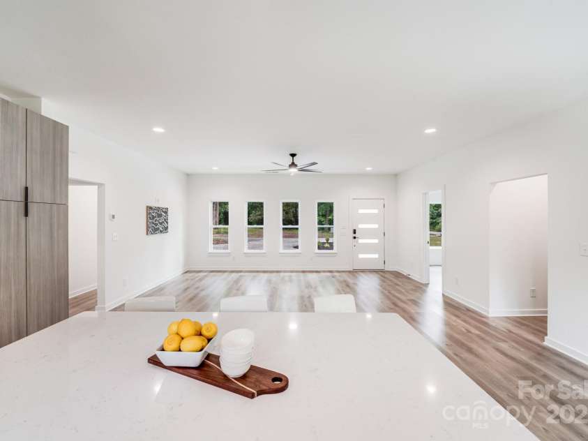 6907 Lancaster Highway, Waxhaw, NC 28173.  MLS# CAR4247480, YatesRealty ID 26742. Large, open great room featuring a full wall of windows, a striking black ceiling fan, and sleek natural wood-look luxury vinyl plank flooring.