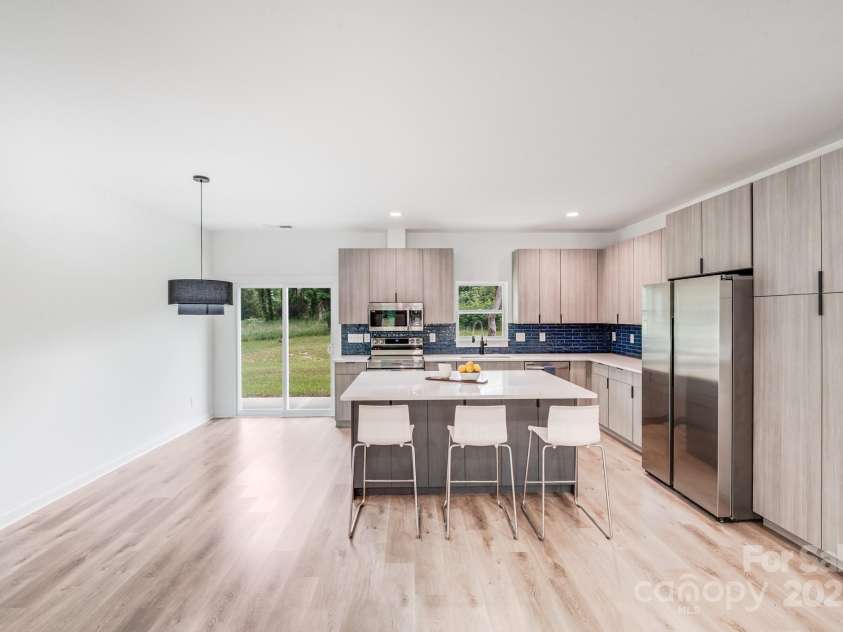 6907 Lancaster Highway, Waxhaw, NC 28173.  MLS# CAR4247480, YatesRealty ID 26742. The gourmet kitchen features a spacious center island, stainless steel appliances — including a stove/oven combination, built-in microwave, dishwasher, and a sleek modern refrigerator — all seamlessly connected to the 