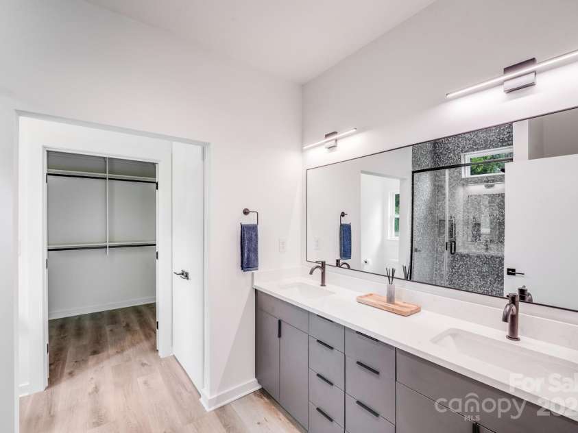 6907 Lancaster Highway, Waxhaw, NC 28173.  MLS# CAR4247480, YatesRealty ID 26742. The luxurious primary bathroom features double sinks with sleek undermount basins set in gleaming quartz countertops, accented by modern black faucets. Stylish black-framed mirror and contemporary lighting above each s