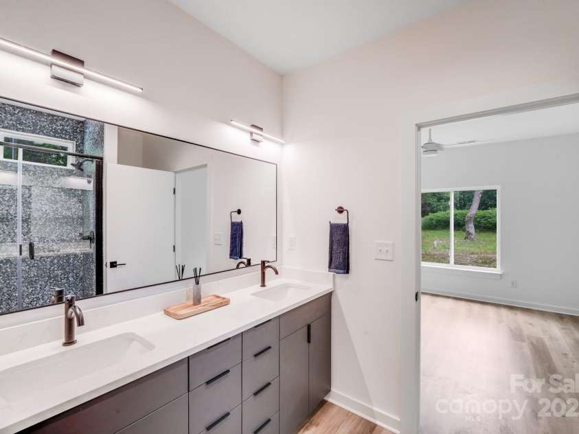 6907 Lancaster Highway, Waxhaw, NC 28173.  MLS# CAR4247480, YatesRealty ID 26742. The primary bathroom features custom dark gray cabinetry with sleek matte black finger pulls with ample cabinetry and drawers for storage. Beautiful penny round tile in shades of blue, gray, and white adds a unique, el