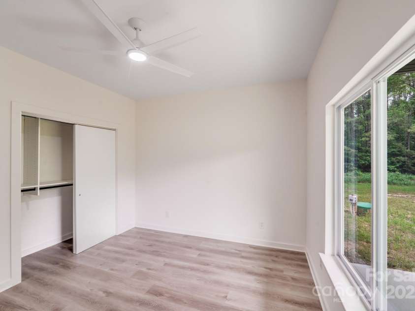 6907 Lancaster Highway, Waxhaw, NC 28173.  MLS# CAR4247480, YatesRealty ID 26742. The secondary bedroom closet features custom white shelving and sleek black hanging rails, offering both stylish design and practical storage.A large double window in the secondary bedroom overlooks the private backyar