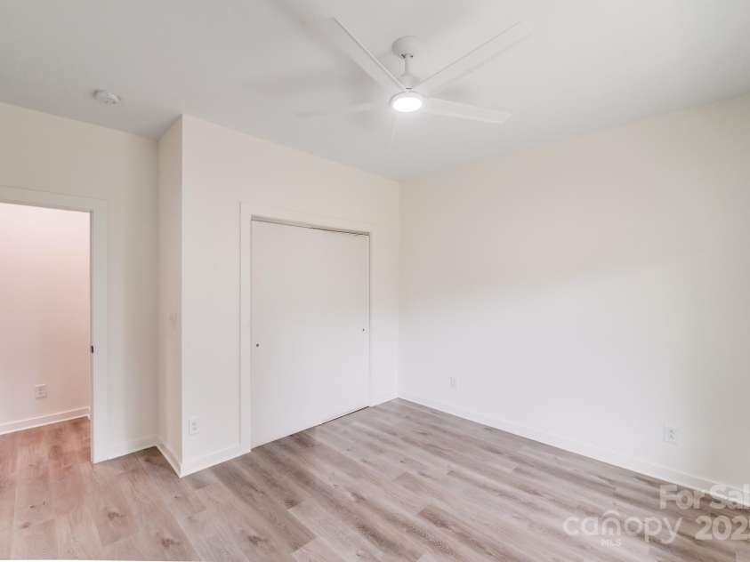 6907 Lancaster Highway, Waxhaw, NC 28173.  MLS# CAR4247480, YatesRealty ID 26742. The secondary bedroom features modern white sliding closet doors, a sleek white ceiling fan, and natural wood-look luxury vinyl plank flooring, creating a fresh, clean, and inviting space.