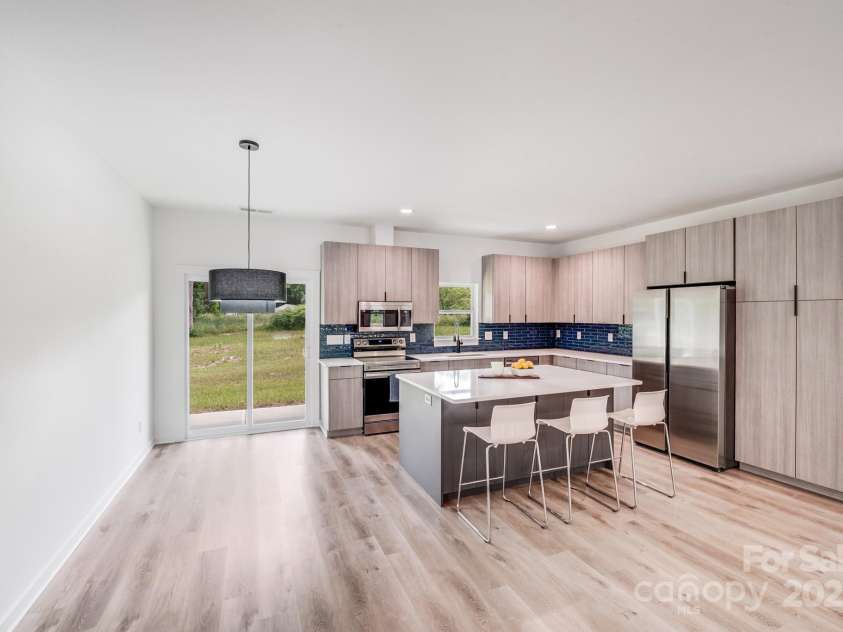 6907 Lancaster Highway, Waxhaw, NC 28173.  MLS# CAR4247480, YatesRealty ID 26742. To the left of the island, the dining area features a sleek black modern light fixture and sliding glass doors that lead to the covered back patio, while recessed can lights brighten the adjacent kitchen area.