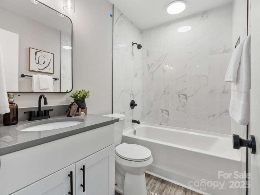 2000 Patio Court, Charlotte, NC 28205.  MLS# CAR4270954, YatesRealty ID 2677. Beautifully renovated modern bathroom. New vanity w/ quartz top. Stunning white shower tile with built-in shampoo niche. All new fixtures and hardware. Light above shower has a built-in fan.