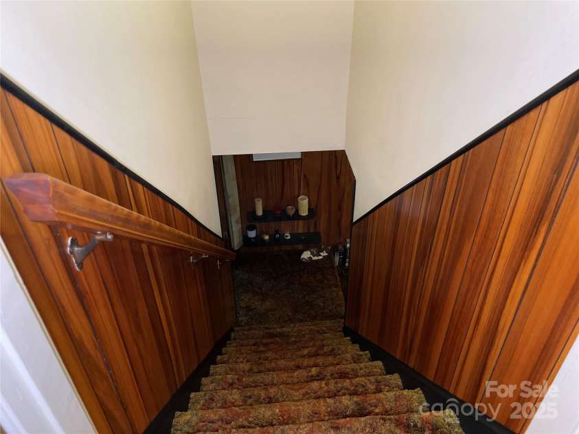 5806 Whitingham Drive, Charlotte, NC 28215.  MLS# CAR4263834, YatesRealty ID 27000. Stairs leading to  Lower Level/Basement. Paneling and black accents lend itself to mid-century modern vibe.