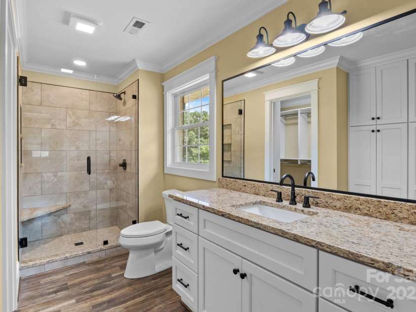 893 Chief Thomas Road, Harmony, NC 28634.  MLS# CAR4278148, YatesRealty ID 27073. Primary bath with granite vanity, walk-in tile shower, modern lighting and additional cabinets