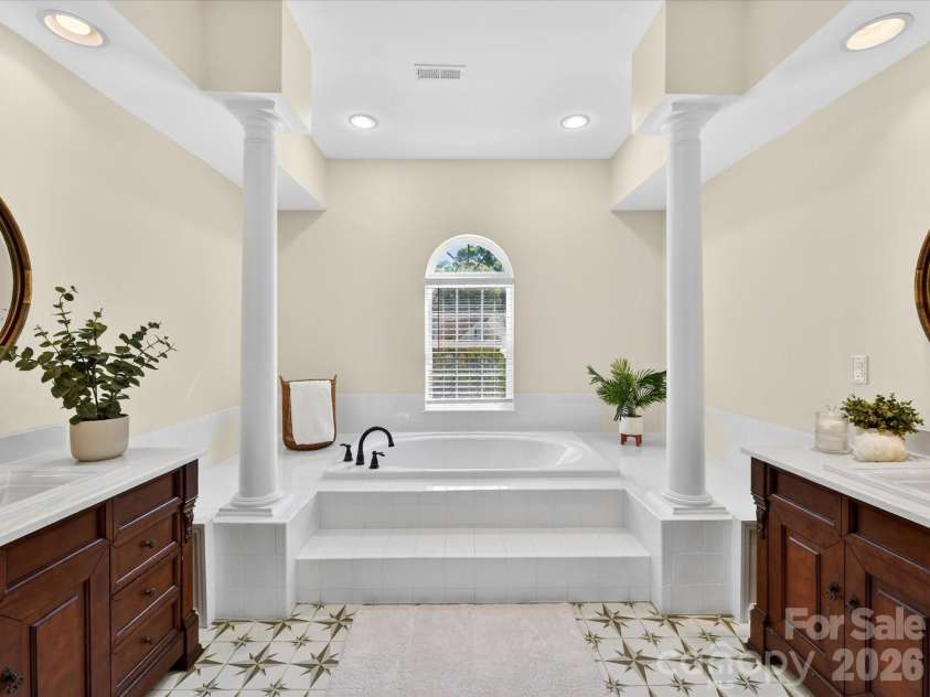 4179 Buckingham Drive, Fort Mill, SC 29707.  MLS# CAR4373781, YatesRealty ID 27110. Luxurious primary bath featuring dual vanities, soaking tub with elegant columns, and separate glass-enclosed shower for a spa-like retreat.