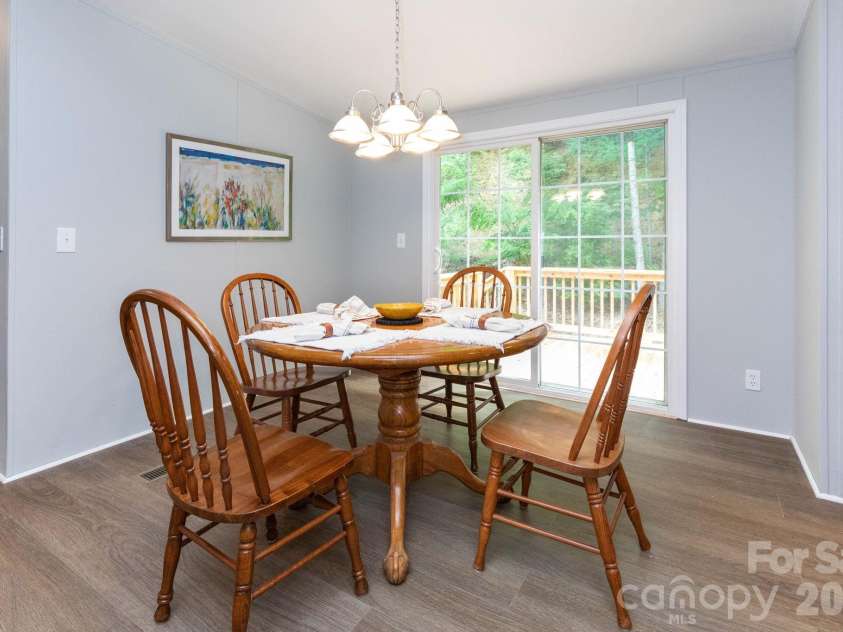 61 Blue Mountain Road, Fairview, NC 28730.  MLS# CAR4381862, YatesRealty ID 27229. Dining Area – Bright dining space with access to the back deck, offering the perfect spot for morning coffee, outdoor dining, or enjoying the surrounding wooded views.