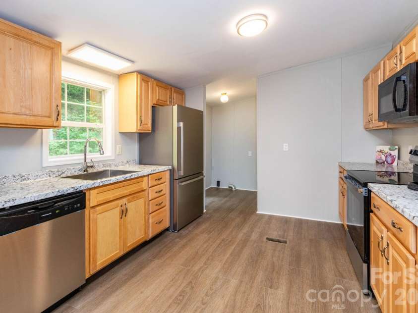 61 Blue Mountain Road, Fairview, NC 28730.  MLS# CAR4381862, YatesRealty ID 27229. Kitchen & Dining Area – Large eat-in kitchen with generous counter space and an adjacent dining area overlooking the peaceful backyard through sliding glass doors.