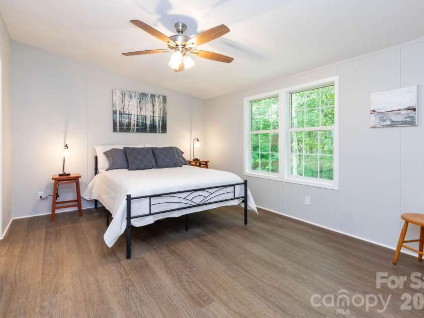 61 Blue Mountain Road, Fairview, NC 28730.  MLS# CAR4381862, YatesRealty ID 27229. Primary Bedroom – Spacious primary suite with updated flooring, soft neutral tones, and large windows that bring in peaceful wooded views and natural light.
