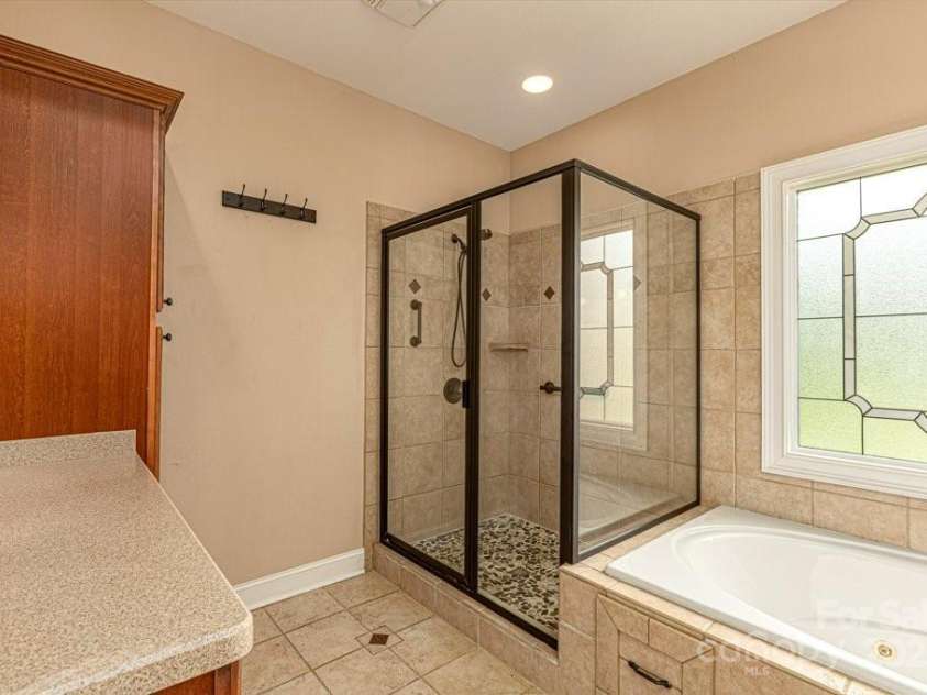 4004 3rd Court, Morganton, NC 28655.  MLS# CAR4269854, YatesRealty ID 27255. Step into relaxation in this beautifully designed primary suite bathroom, featuring a spacious tile walk-in shower with sleek glass enclosure and oil-rubbed bronze fixtures. A stunning pebble stone shower floor adds a spa-l