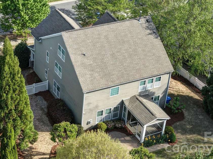 148 Byers Commons Drive, Mooresville, NC 28117.  MLS# CAR4368080, YatesRealty ID 27301. Aerial rear view of home with the backyard freshly mulched and accented by blooming flowers and mature trees providing privacy on a desirable corner lot with sidewalks.