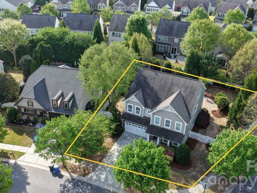 148 Byers Commons Drive, Mooresville, NC 28117.  MLS# CAR4368080, YatesRealty ID 27301. Aerial view of the home with represented lot lines outlining a fully fenced, expansive lot featuring mature trees and exceptional privacy.