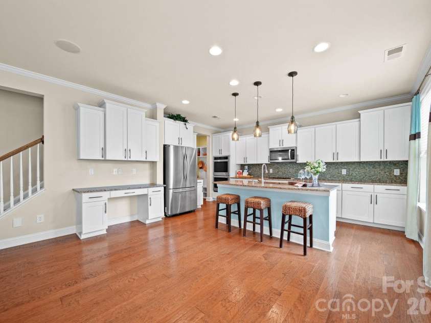 148 Byers Commons Drive, Mooresville, NC 28117.  MLS# CAR4368080, YatesRealty ID 27301. Beautiful kitchen with granite countertops, abundant cabinet and counter space, a stylish tile backsplash, center island, stainless steel appliances, and designer light fixtures.