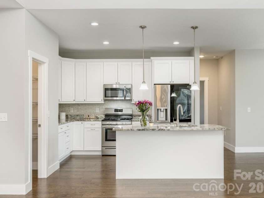 36 Windy Acres Knoll Drive, Hendersonville, NC 28792.  MLS# CAR4377336, YatesRealty ID 27383. Kitchen – Bright, open-concept kitchen featuring abundant white cabinetry, granite countertops, stainless steel appliances, a spacious center island/breakfast bar with room for seating, and a large walk-in 