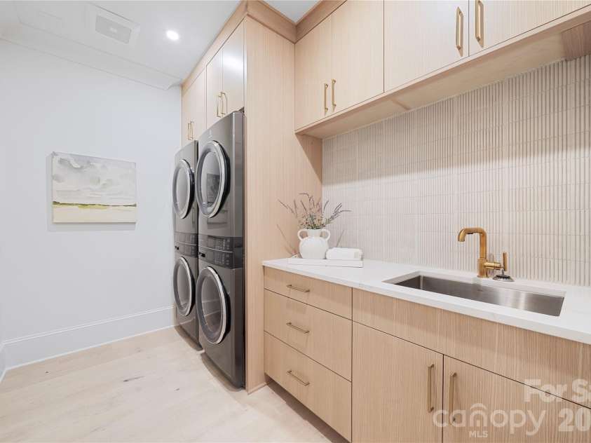 409 Queens Road, Charlotte, NC 28207.  MLS# CAR4425871, YatesRealty ID 274. The well-appointed laundry room provides a double washer, and a double dryer setup! This unique private laundry provides extensive custom cabinetry for storage, a double wide stainless steel utility sink and generous counter