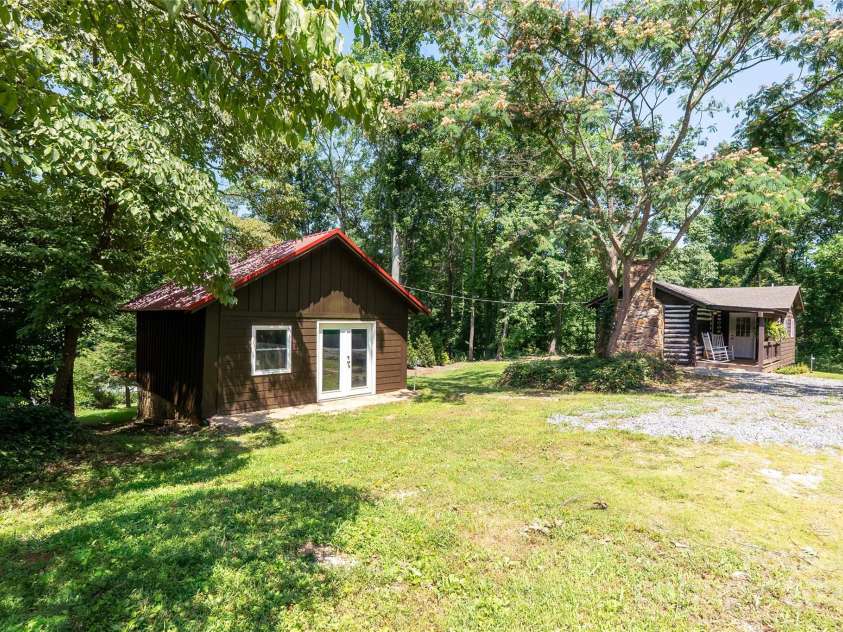 225 Wilderness Road, Tryon, NC 28782.  MLS# CAR4272632, YatesRealty ID 27434. Workshop with cabin in background.