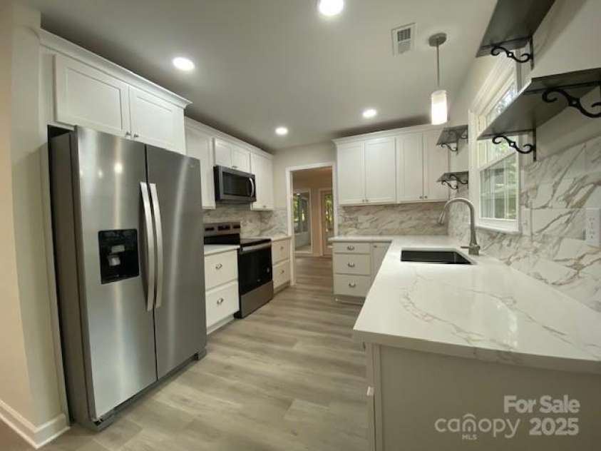 709 Falls Church Road, Charlotte, NC 28270.  MLS# CAR4275080, YatesRealty ID 27488. Kitchen, Quartz Countertops, tile backsplash and stainless appliances. Recessed lights with dimmer