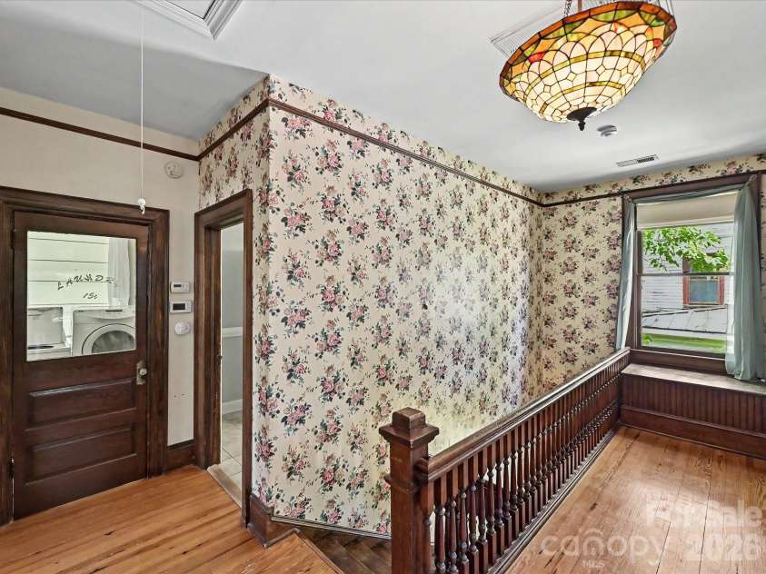 702 Hayne Street, Monroe, NC 28112.  MLS# CAR4376608, YatesRealty ID 27571. Character-rich upper landing showcasing intricate wallpaper, stained glass accents, and period charm.