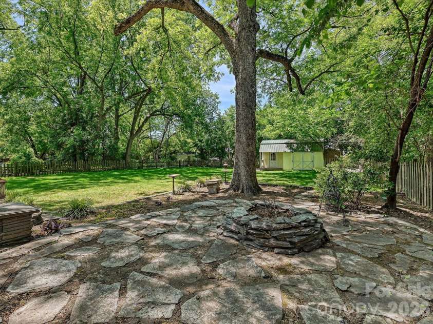 702 Hayne Street, Monroe, NC 28112.  MLS# CAR4376608, YatesRealty ID 27571. Charming stone patio offering a peaceful retreat beneath the shade of towering canopy trees.