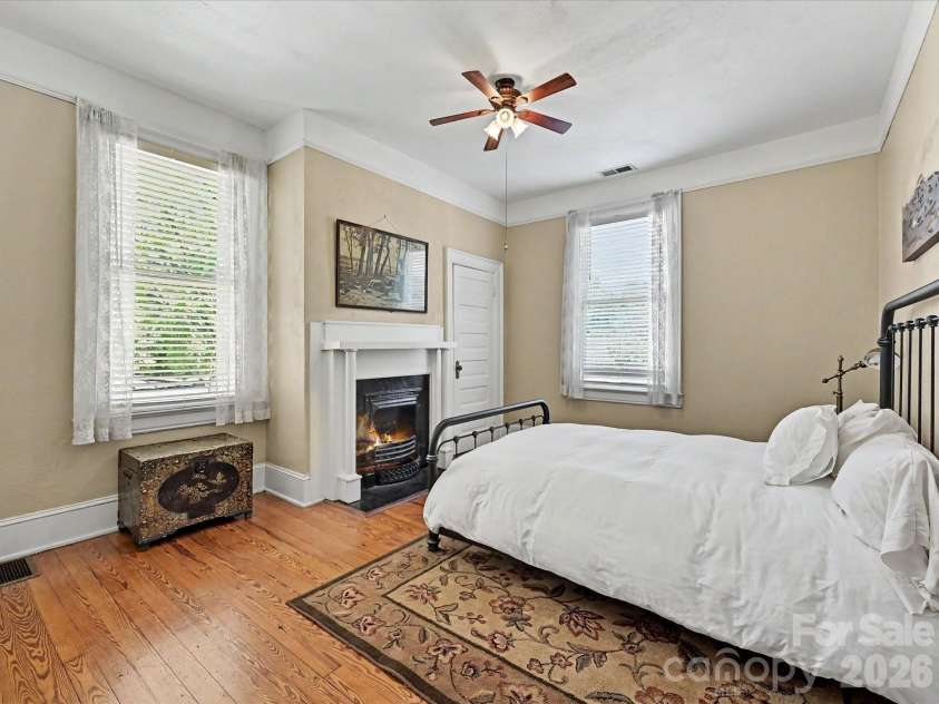 702 Hayne Street, Monroe, NC 28112.  MLS# CAR4376608, YatesRealty ID 27571. Cozy bedroom with fireplace, hardwood floors, and abundant natural light.