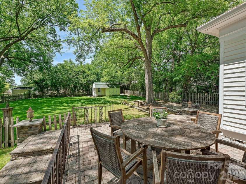 702 Hayne Street, Monroe, NC 28112.  MLS# CAR4376608, YatesRealty ID 27571. Expansive patio and dining area surrounded by mature trees and serene outdoor beauty.