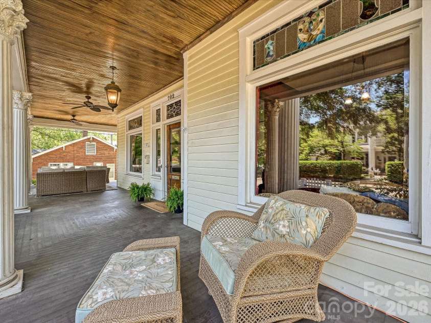 702 Hayne Street, Monroe, NC 28112.  MLS# CAR4376608, YatesRealty ID 27571. Inviting covered porch featuring warm wood ceilings and elegant outdoor seating areas.