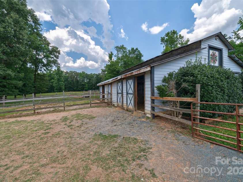 7411 Davis Road, Waxhaw, NC 28173.  MLS# CAR4278062, YatesRealty ID 27614. SIDE OF THE BARN SHOWING THAT THE STALLS HAVE ACCESS TO PADDOCKS WHICH CAN BE USED AS DRY LOTS