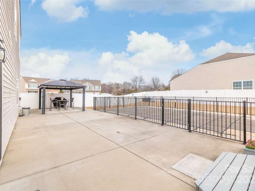 3215 Roan Street, Concord, NC 28027.  MLS# CAR4328709, YatesRealty ID 2767. The oversized patio surrounds the pool area, featuring an additional raised deck surrounded by a privacy fence. 