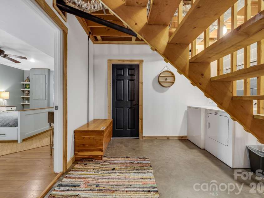 694 Boulder Road, Marshall, NC 28753.  MLS# CAR4384488, YatesRealty ID 27681. Stairs from main floor down to basement. Flex Room and Private Closet w/ roll up door to outside to the left. Indoor air handler straight ahead. 
