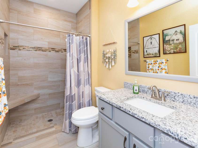 605 Red Bank Road, Waynesville, NC 28786.  MLS# CAR4313671, YatesRealty ID 27707. Guest bath has a low entry, fully tiled shower with seat and beautiful vanity with granite counters and undermount sink