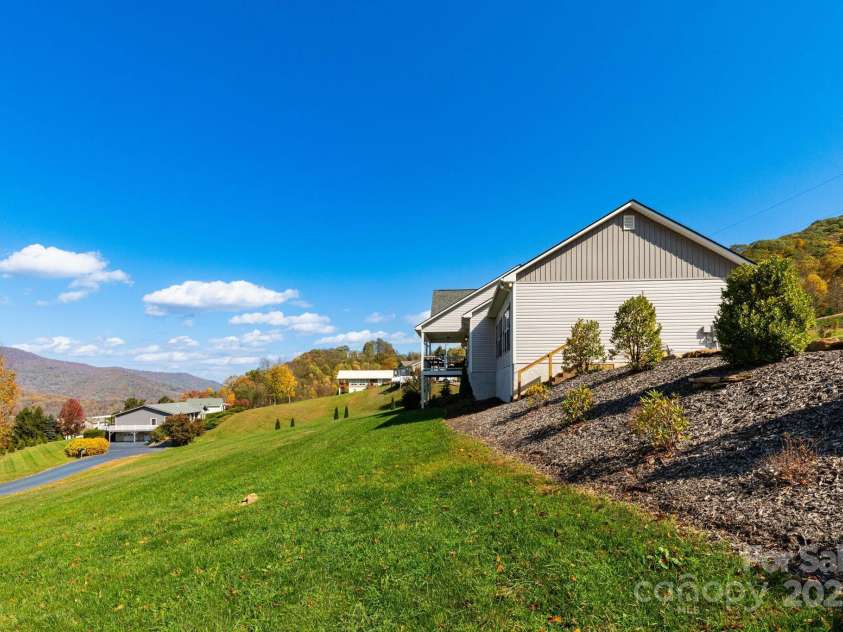 605 Red Bank Road, Waynesville, NC 28786.  MLS# CAR4313671, YatesRealty ID 27707. Side view of home with gently sloping back yard.