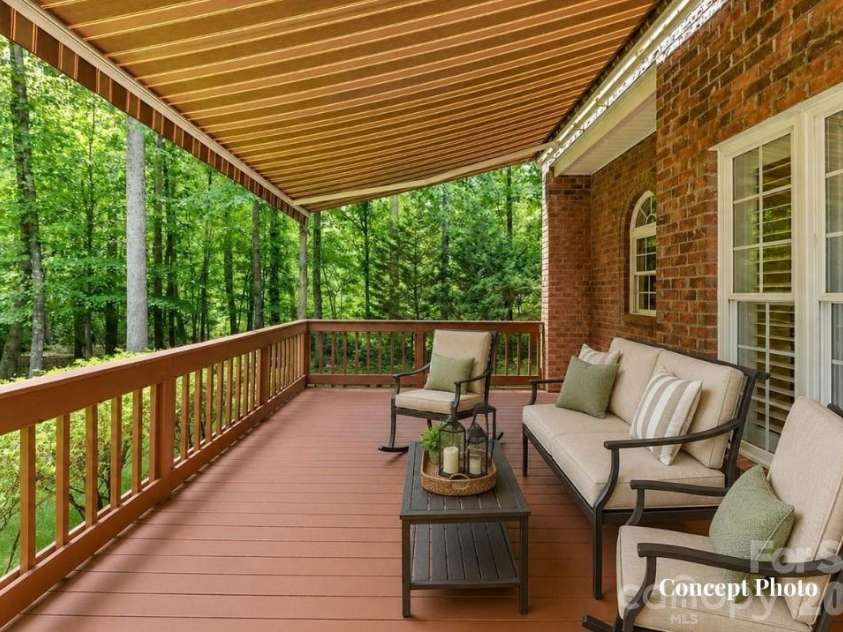 11615 Hidden Forest Lane, Davidson, NC 28036.  MLS# CAR4386264, YatesRealty ID 27816. Concept photo of virtually staged covered deck featuring a retractable awning and serene views of the private, wooded backyard.