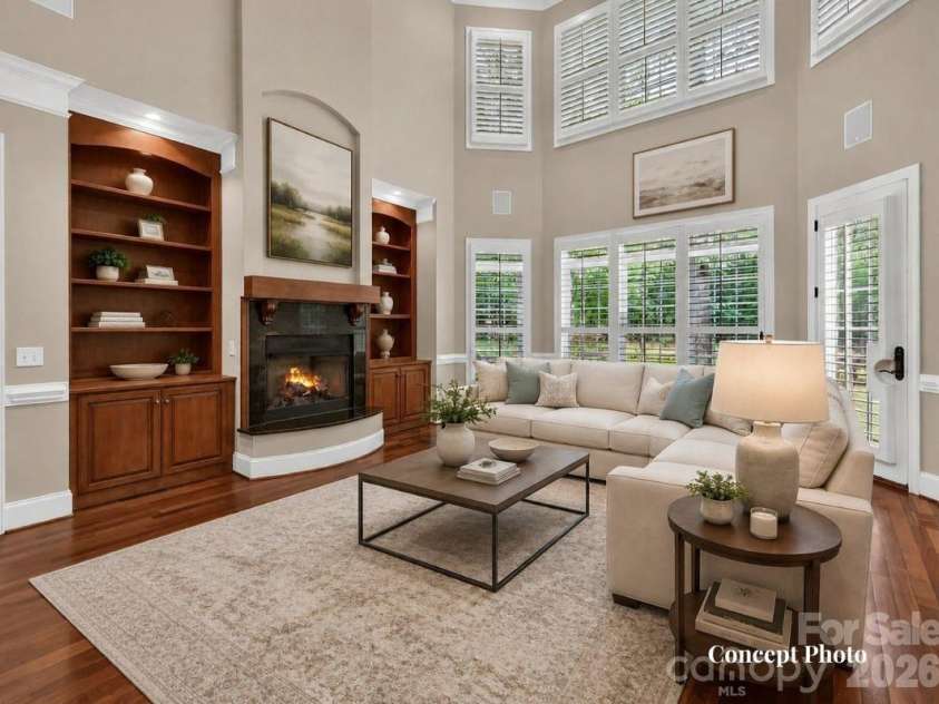 11615 Hidden Forest Lane, Davidson, NC 28036.  MLS# CAR4386264, YatesRealty ID 27816. Concept photo of virtually staged stunning two-story great room features soaring ceilings, custom built-ins, expansive windows, and a cozy fireplace with seamless flow into the kitchen and breakfast area.