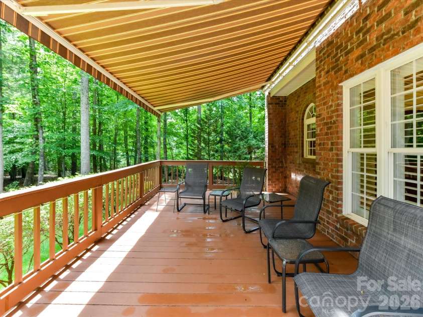 11615 Hidden Forest Lane, Davidson, NC 28036.  MLS# CAR4386264, YatesRealty ID 27816. Enjoy peaceful outdoor living on the covered deck featuring a retractable awning and serene views of the private, wooded backyard.