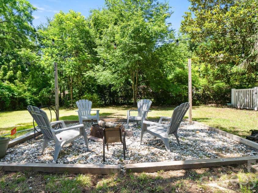 3442 Matthews Indian Trail Road, Matthews, NC 28104.  MLS# CAR4388831, YatesRealty ID 27958. Charming firepit gathering area surrounded by mature trees and string lighting.