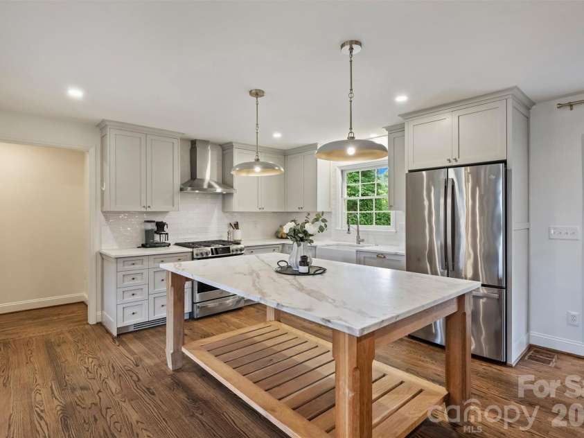 601 Lansdowne Road, Charlotte, NC 28270.  MLS# CAR4388769, YatesRealty ID 28037. The chef's kitchen features marble countertops, a large island, gas range, and walk-in pantry.