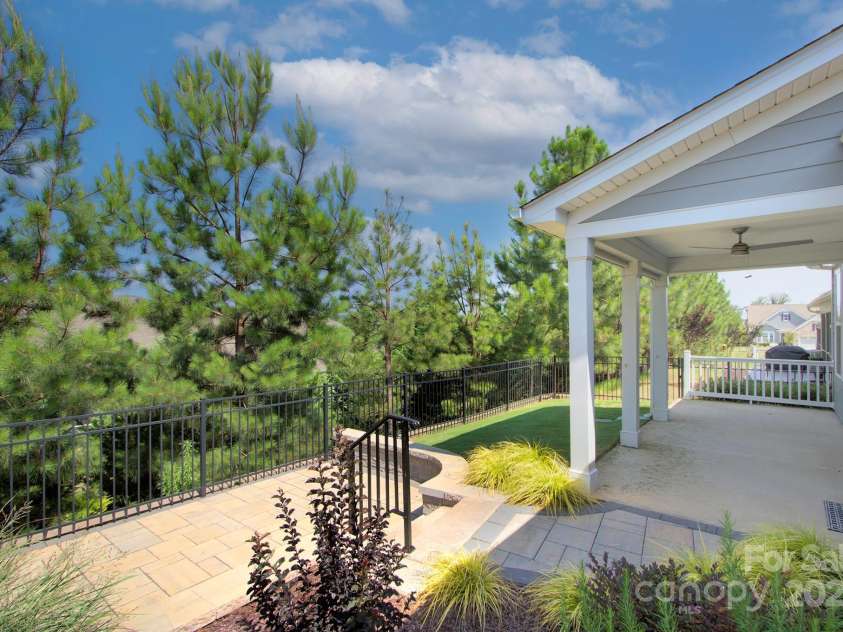 5527 Cheerful Lane, Charlotte, NC 28215.  MLS# CAR4275434, YatesRealty ID 28049. Covered porch with roll down shades, ceiling fan.  There is an uncovered area on the paio as well and a different view of the step down paver patio with new handrail