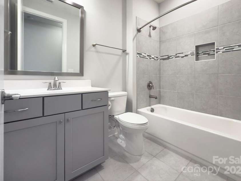 5527 Cheerful Lane, Charlotte, NC 28215.  MLS# CAR4275434, YatesRealty ID 28049. Second full bathroom- easily accessible from Bedroom 2/ office.   Large tub with tile surround, raised vanity, comfort height toilet and tiled flooring   Framed mirror remains