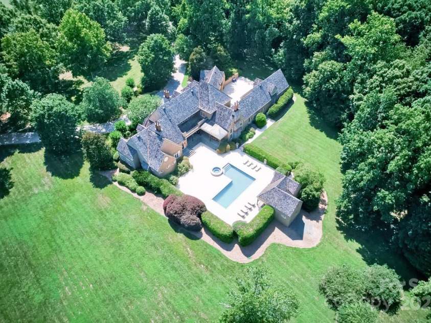 343 Wester Brewlands Road, Iron Station, NC 28080.  MLS# CAR4284507, YatesRealty ID 28060. A Private Sanctuary Spread Across Acres! A breathtaking aerial reveals the full scope of this exceptional property—from lush lawns and mature trees to the resort-style pool area, all surrounded by nature’s pri