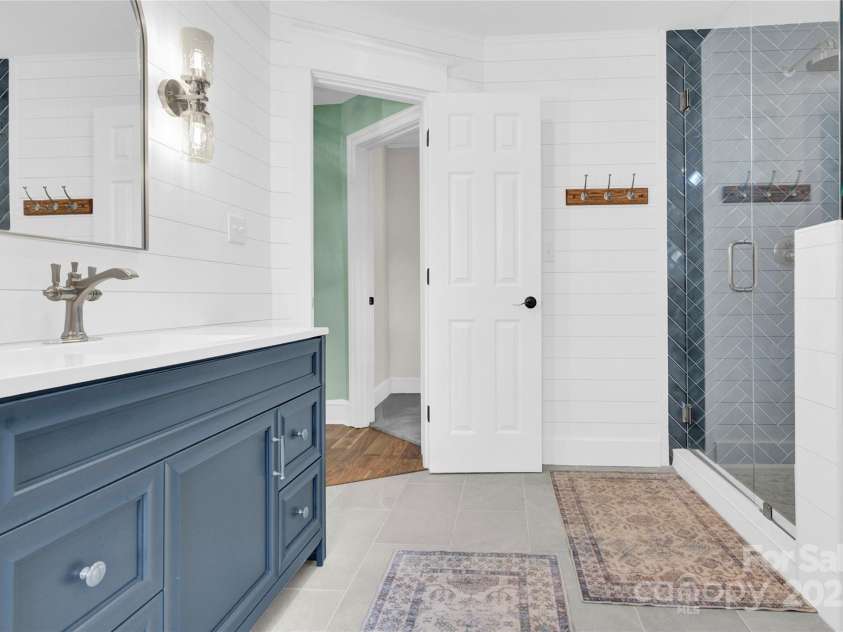 832 Kemp Road, Mooresville, NC 28117.  MLS# CAR4264266, YatesRealty ID 28181. Main bathroom. Vanity with quartz sink, tiled shower and floor, shiplap on walls.