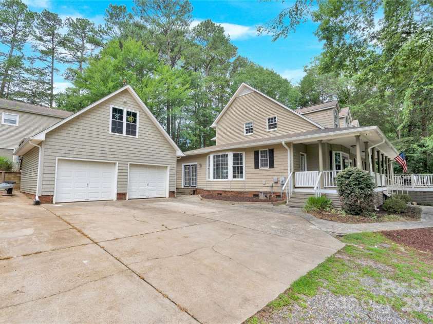 832 Kemp Road, Mooresville, NC 28117.  MLS# CAR4264266, YatesRealty ID 28181. View from driveway.  House shown with wrap around porch, two car garage with office above, space for a boat on the side of the garage as well as the outbuilding behind the garage.