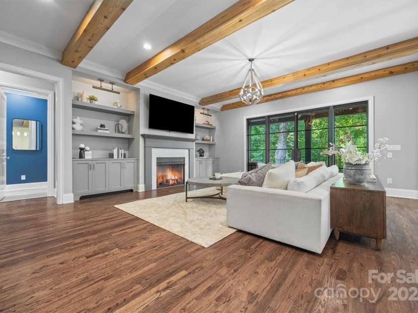 1223 Home Place, Matthews, NC 28105.  MLS# CAR4265332, YatesRealty ID 28217. The main living area features a gas fireplace surrounded by custom built-ins wired with ambient light and leads to the covered back porch.
