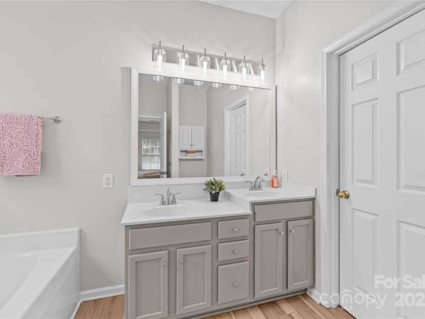 3018 Early Rise Avenue, Indian Trail, NC 28079.  MLS# CAR4283685, YatesRealty ID 28251. Primary bathroom features just painted double-sink vanity with new faucets, new light fixture, soaking tub, framed mirror, walk-in closet.