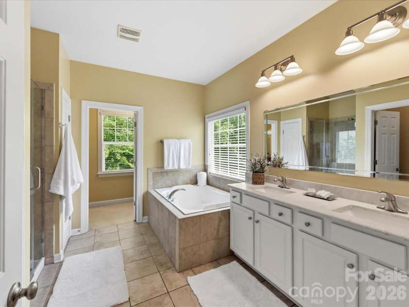 8611 Covedale Crossings Circle, Cornelius, NC 28031.  MLS# CAR4378956, YatesRealty ID 28395. Luxurious primary bath features dual vanities, soaking tub, separate tiled shower, and abundant natural light creating a spa-like retreat.